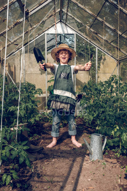 Boy fooling around in greenhouse — Stock Photo