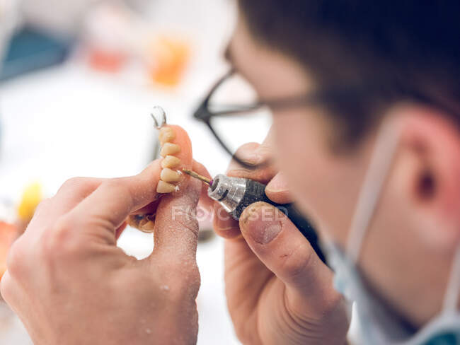 Crop man applying substance on denture — Stock Photo