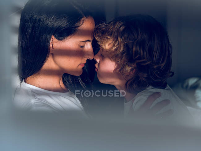 Мати торкається носа з сином на сонячному світлі — стокове фото