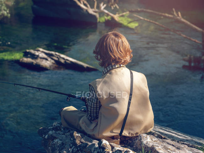 Junge sitzt und fischt — Stockfoto