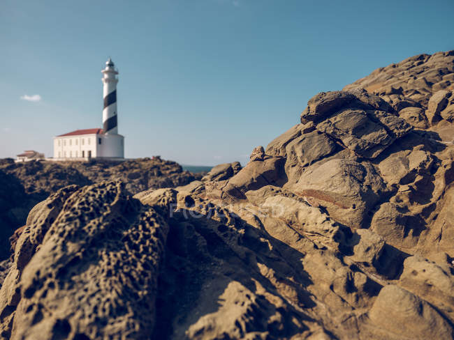 Big rocky coastal hill and lighthouse — Stock Photo