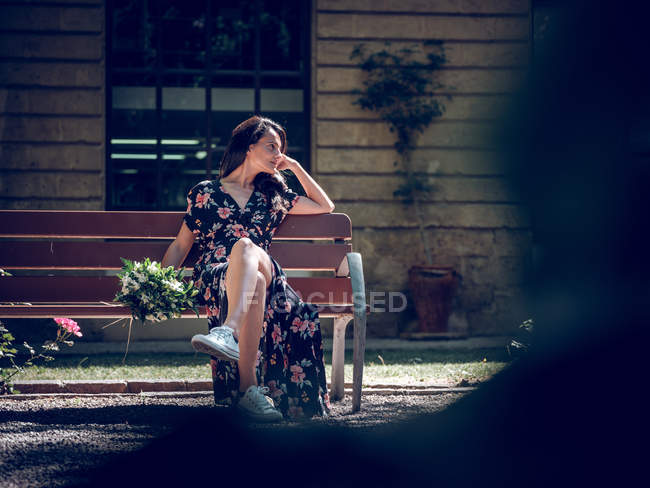 Frau mit Blumenstrauß auf Bank — Stockfoto