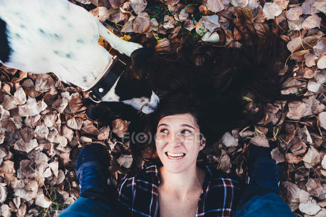 Женщина с собакой, лежащей в листве — стоковое фото
