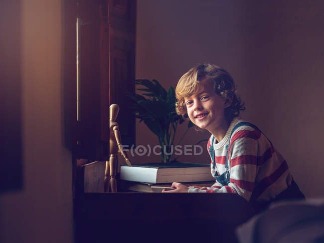 Niño con libro sentado en la mesa - foto de stock