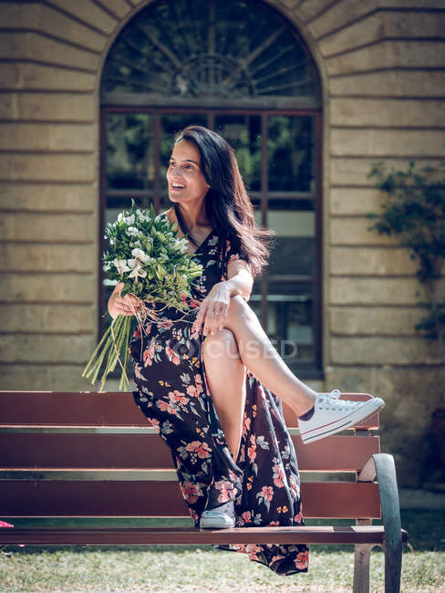 Femme avec bouquet de fleurs sur banc — Photo de stock