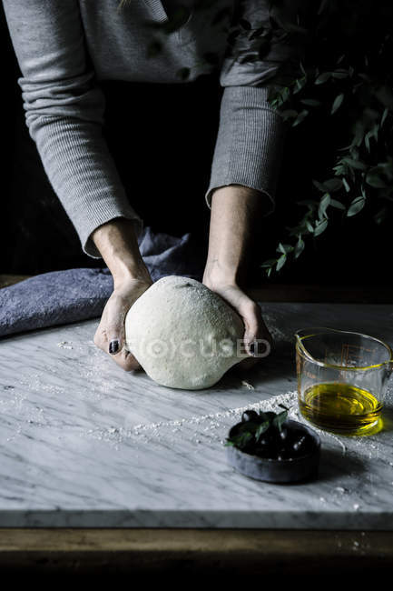 Mains féminines pétrissant la pâte — Photo de stock