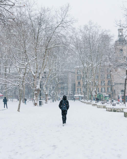 Persona con mochila caminando por la calle nevada en Bilbao, España . - foto de stock
