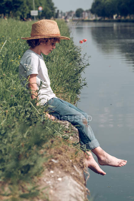 Маленький хлопчик розмахує ногами над водою — стокове фото