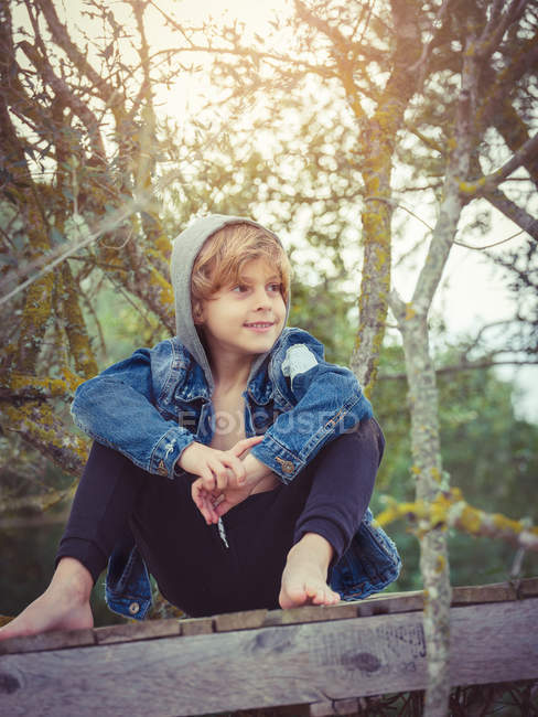 Petit garçon assis sur une jetée en bois — Photo de stock