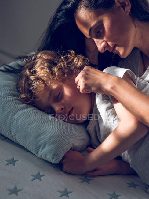 Madre tocando dormir hijo - foto de stock