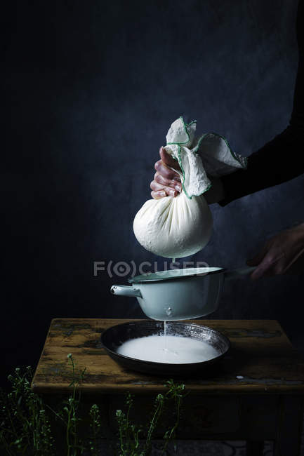 Vista cortada de mãos de cozinheiro apertando queijo cottage na mesa . — Fotografia de Stock