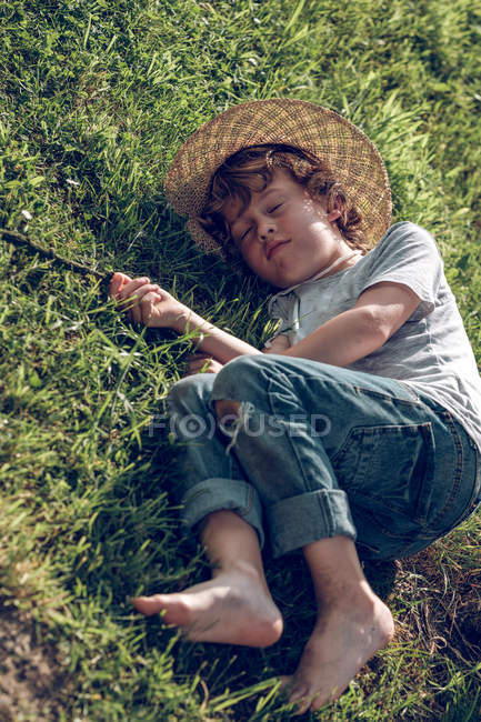 Menino deitado na grama fresca verde — Fotografia de Stock
