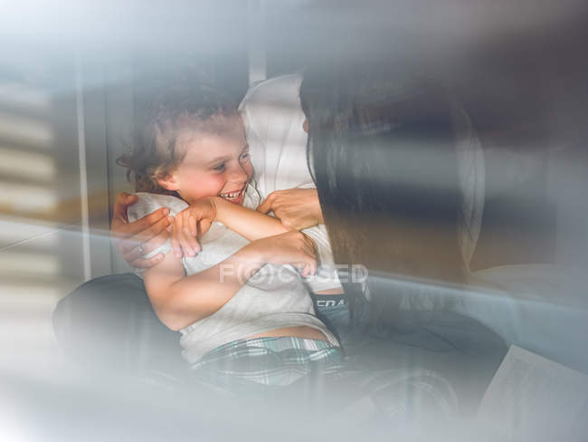 Mother tickling son in sunlight — Stock Photo