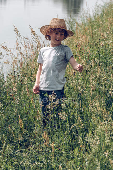 Boy standing in grass at river — Stock Photo