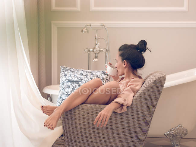 Junge Frau liegt im Sessel im Badezimmer — Stockfoto