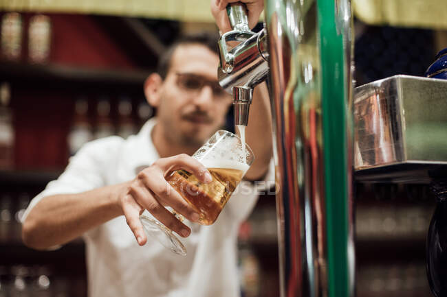 Camarero tirando de una cerveza en un pub - foto de stock