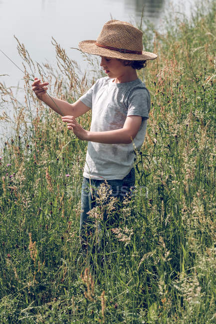 Хлопчик стоїть у траві на річці — стокове фото
