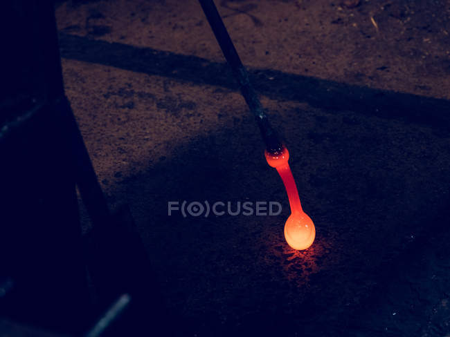 Red hot glass prepared for blowing on pipe on glassblowing factory. — Stock Photo
