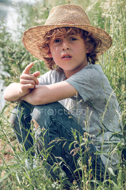 Boy sitting in grass at river — Stock Photo