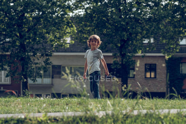Garçon souriant posant sur la pelouse — Photo de stock