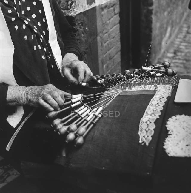 Black and white shot of senior woman sitting on street of Belgium with handcraft in leisure. — Stock Photo