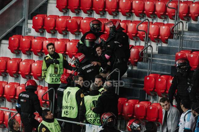 Policemen carrying fan from tribune on stadium — Stock Photo