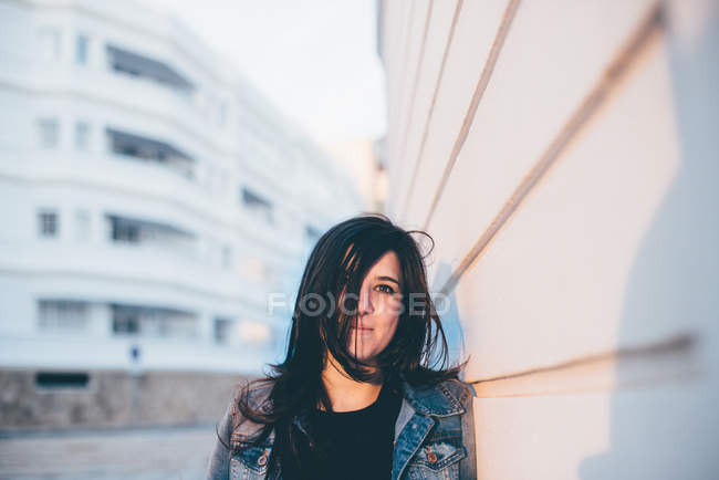 Woman standing at white wall — Stock Photo