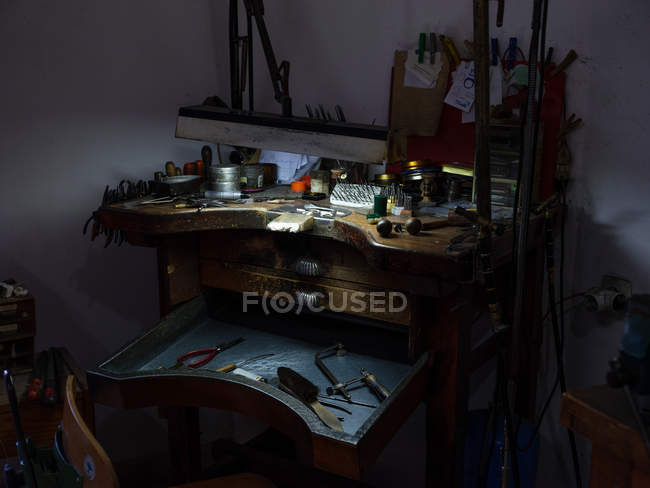 Tavolo con vari strumenti e luce nella vecchia fabbrica di gioielli . — Foto stock