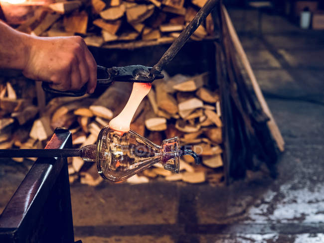Cropped view of unrecognizable glassblower making glass vase on factory. — Stock Photo