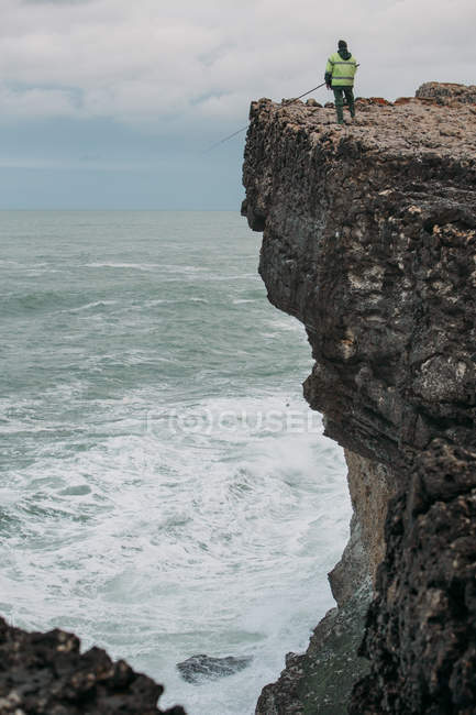 Homme pêche sur grande falaise — Photo de stock