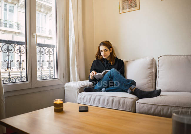 Mujer relajante con libro en casa - foto de stock