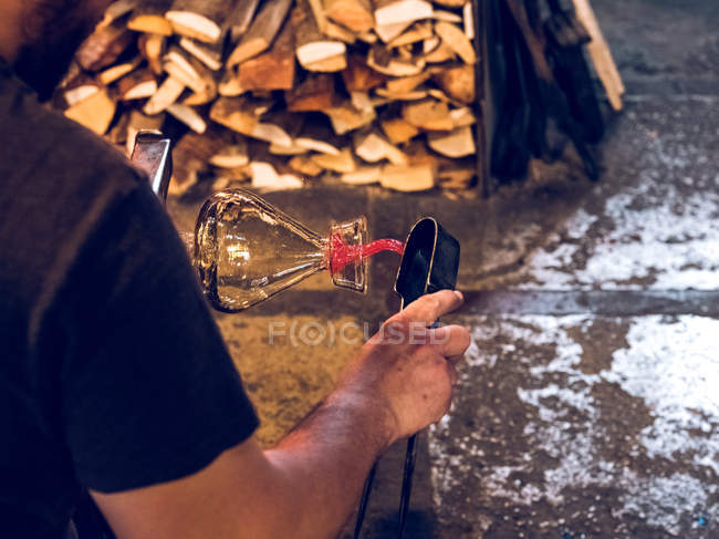 Cropped view of unrecognizable glassblower making glass vase on factory. — Stock Photo