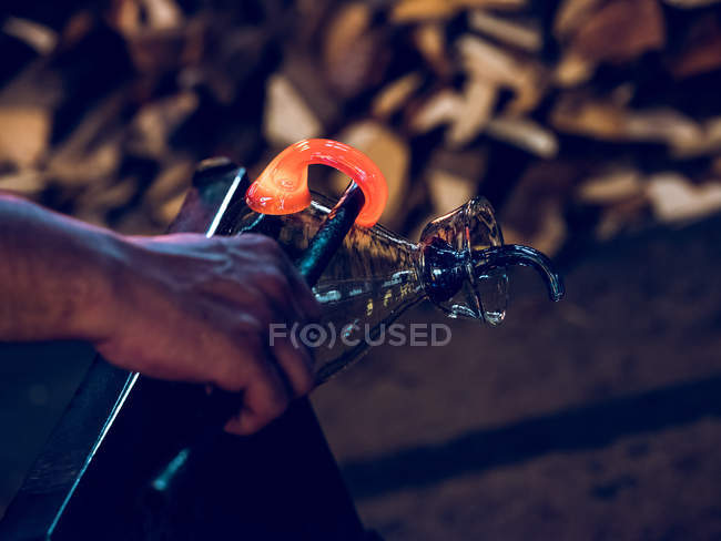 Artisan méconnaissable formant le support sur une cruche en verre sur une usine de soufflage du verre . — Photo de stock