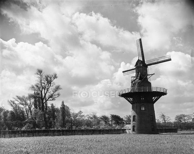 Vista in bianco e nero del mulino a vento in legno alterato collocato nel campo del Belgio alla luce del sole
. — Foto stock