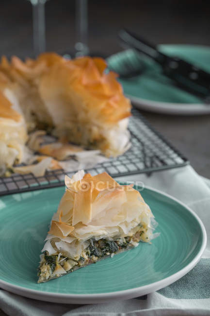 Pedazo de pastel tradicional de espinacas griegas spanakopita en plato azul - foto de stock