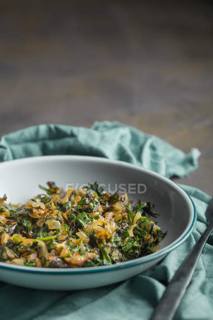 Stuffing for traditional spanakopita spinach pie in bowl on cloth — Stock Photo