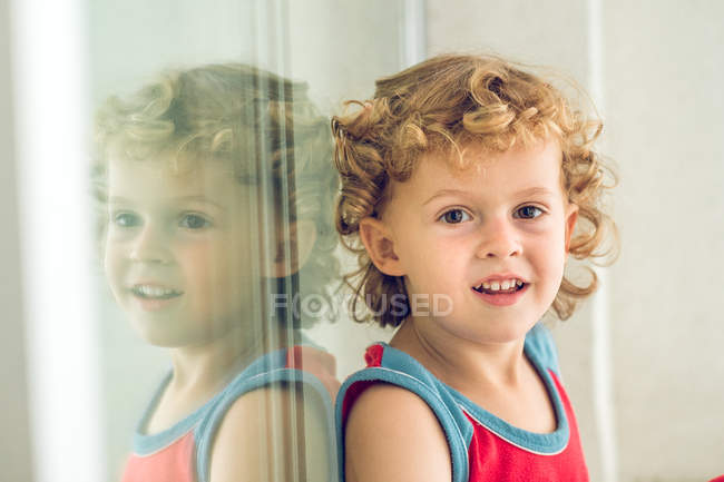 Garçon souriant à la fenêtre — Photo de stock