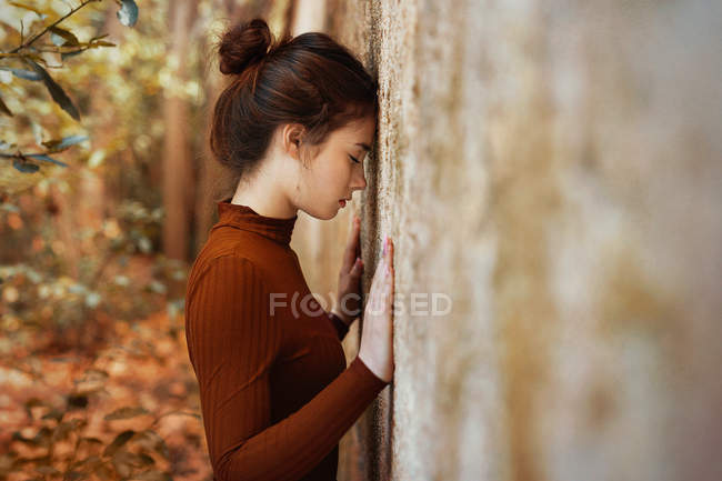 Mujer inclinada frente contra la pared - foto de stock