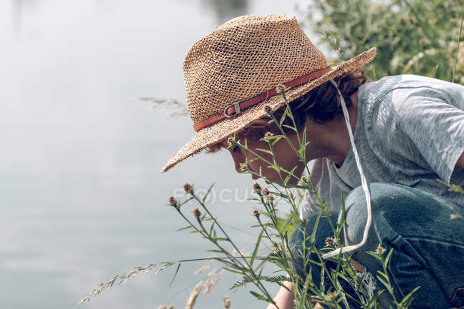 Хлопчик сидить на траві і грає з водою — стокове фото