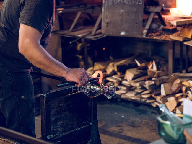 Unrecognizable glassblower forming holder on glass jug on factory. — Stock Photo