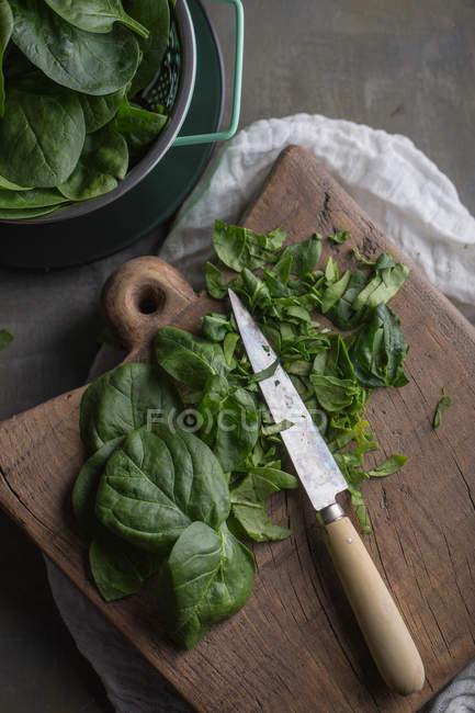 Partly chopped green spinach leaves on wooden chopping board — Stock Photo