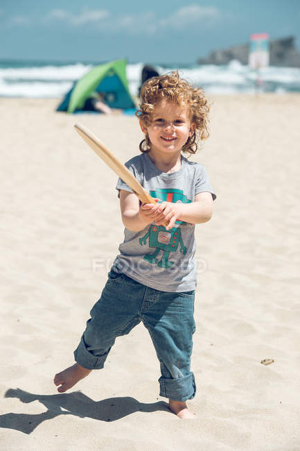 Boy with wooden racket on beach — Stock Photo