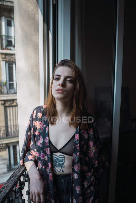 Чуттєва татуйована жінка стоїть біля вікна — стокове фото