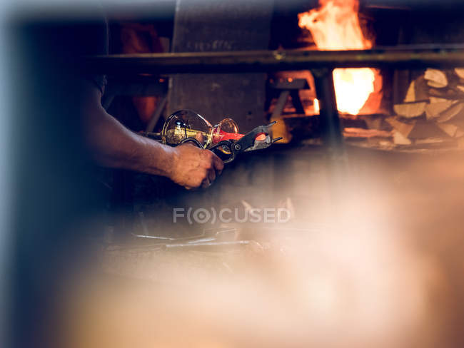 Cropped view of unrecognizable glassblower working on factory and making glass decoration. — Stock Photo