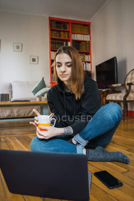 Женщина сидит с ноутбуком на полу — стоковое фото