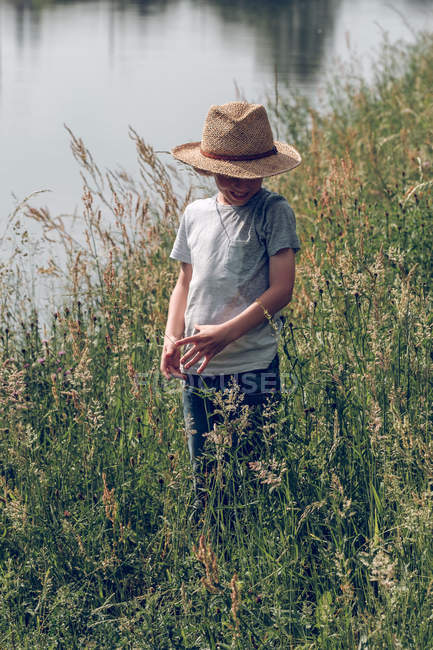 Boy standing in grass at river — Stock Photo