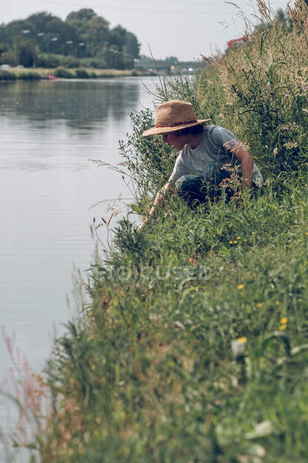 Ragazzo seduto in erba al fiume — Foto stock