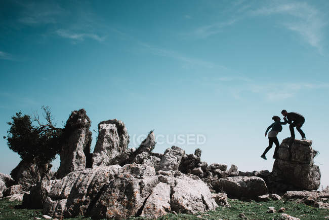 Man helping woman climbing on rock — Stock Photo