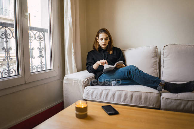 Жінка розслабляється з книгою вдома — стокове фото