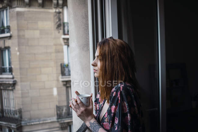 Frau steht mit Tasse auf Balkon — Stockfoto